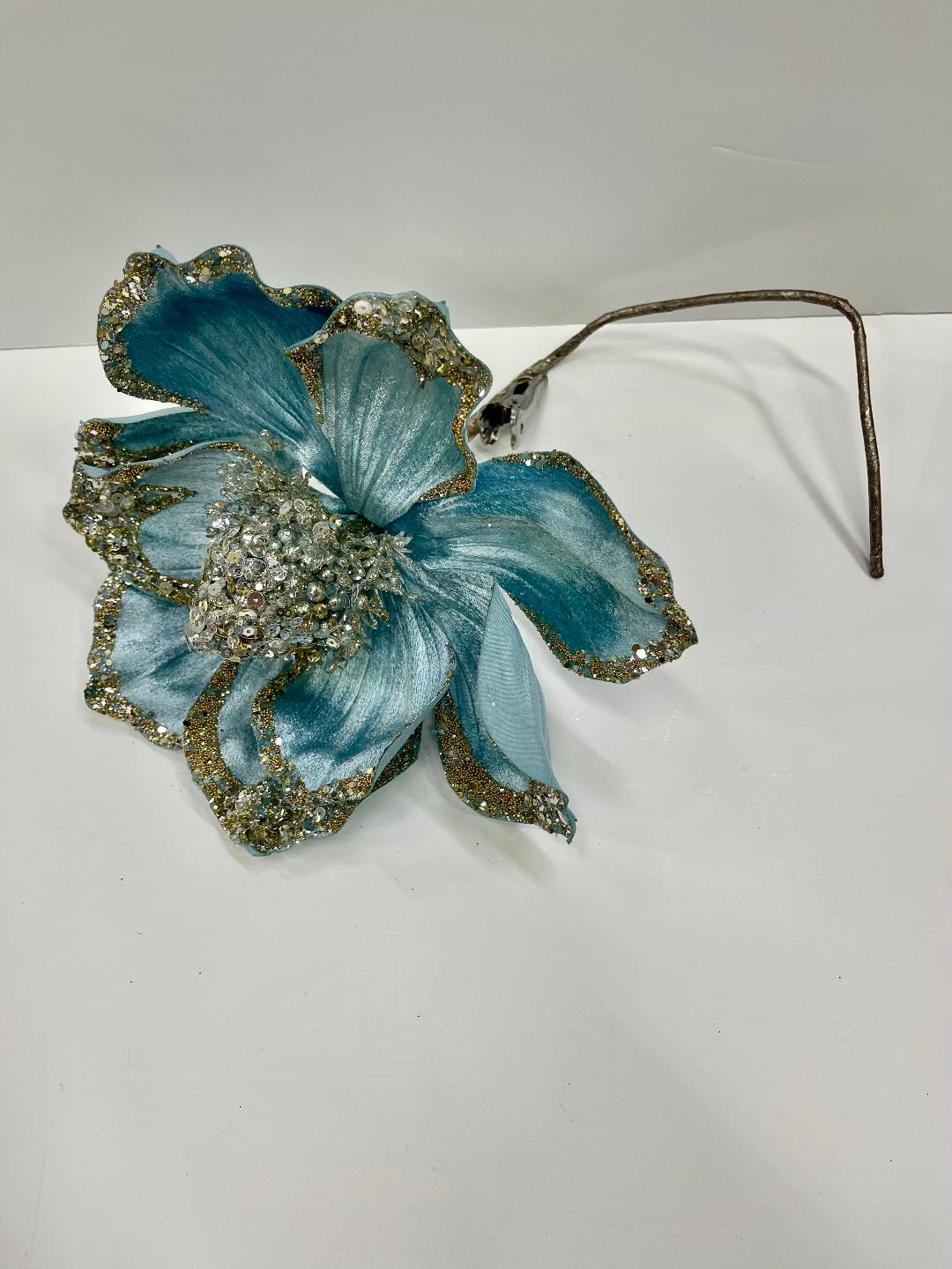 A hair clip featuring a blue and silver floral design with a rhinestone center.