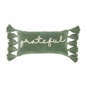A rectangular green velvet pillow with the word 'grateful' written in a white script font, adorned with green tassels on the sides.