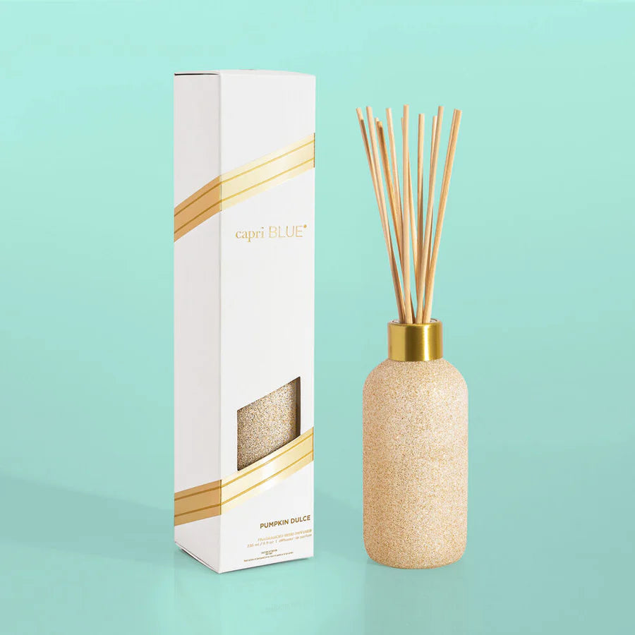 A reed diffuser with clear bottle and gold accents, accompanied by packaging with a window displaying the product.
