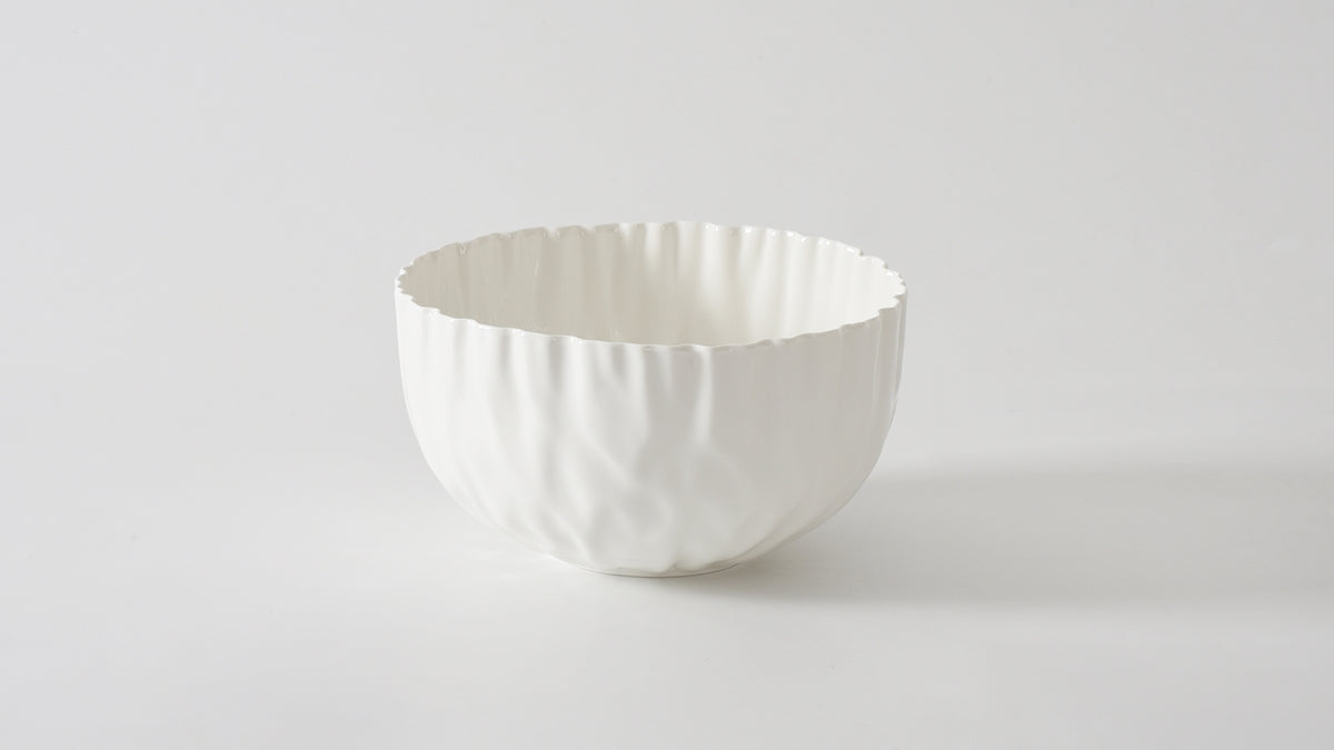 A medium-sized white bowl with a textured exterior on a plain background.