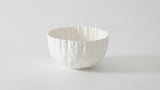 A medium-sized white bowl with a textured exterior on a plain background.