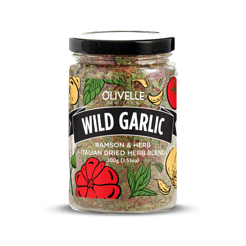 A clear plastic jar containing dried herbs with a label that reads 'Wild Garlic' and the brand name 'Olivelle'. The jar is sealed with a black lid and the product is depicted with a colorful graphic of garlic and tomato, indicating the flavor profile.