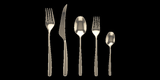 A set of five silver flatware pieces including a dinner fork, dinner knife, soup spoon, and teaspoon, all laid out on a plain background.