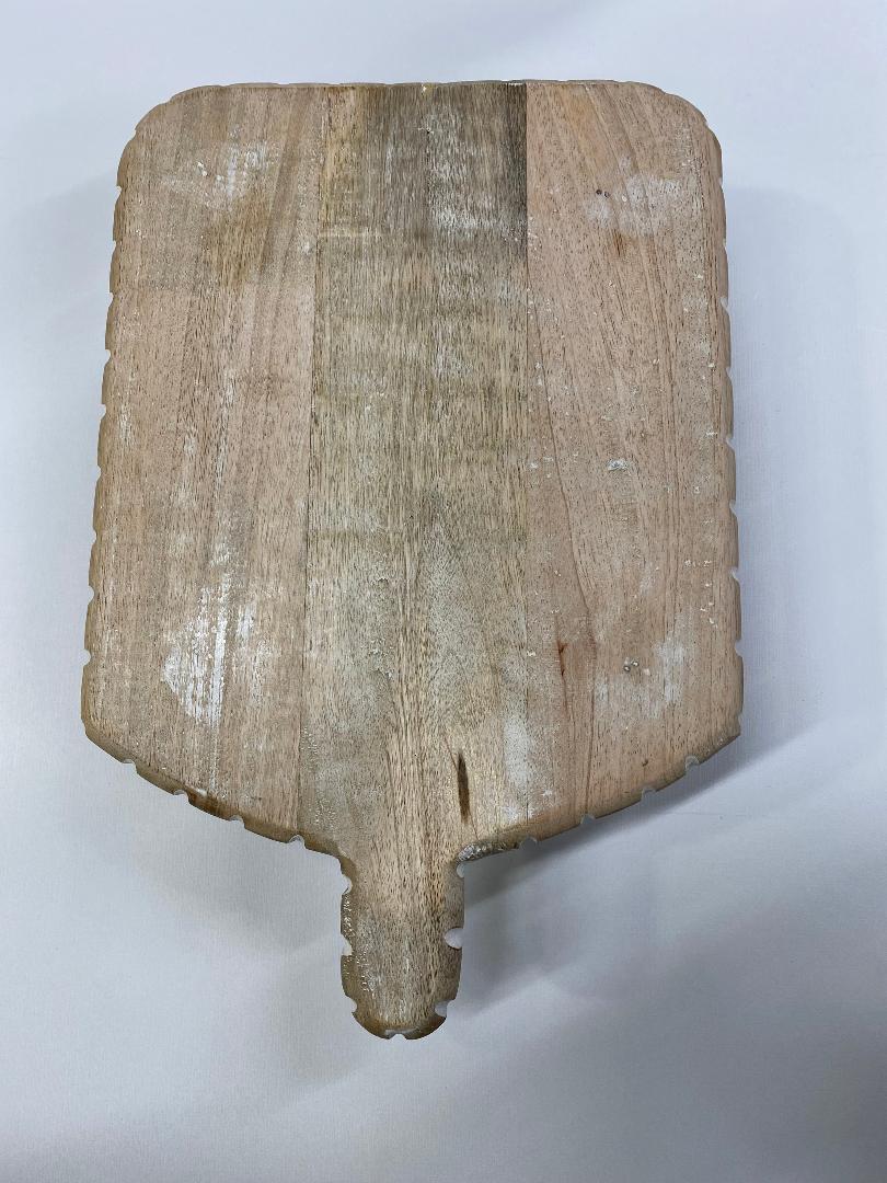 A beige-colored LG carved wood serving board with a natural wood pattern and a handle.
