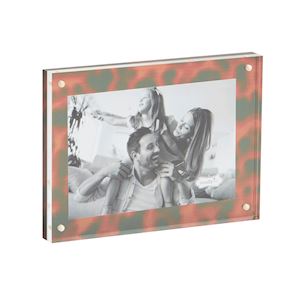 A picture frame with a tortoise shell-like pattern, displaying an old photograph of two individuals sitting close by a lake.