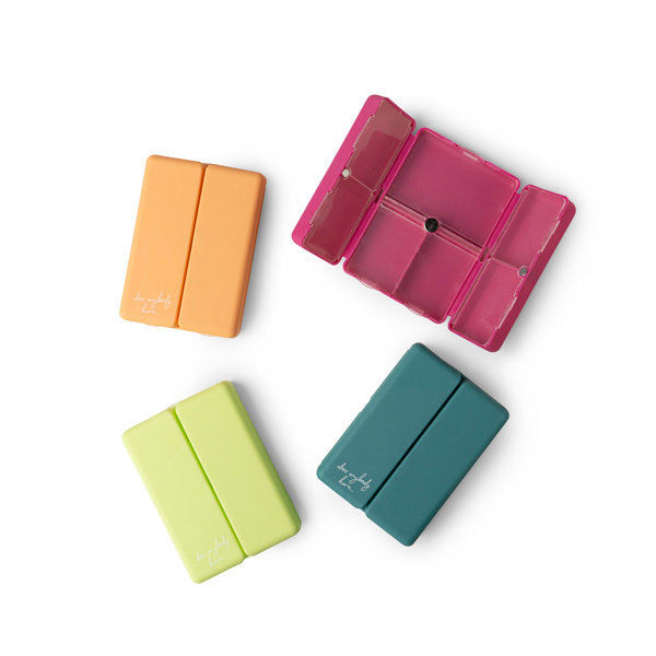 A collection of four vitamin and pill cases in different colors: orange, pink, green, and blue.