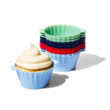 A set of OXO silicone baking cups in various sizes and colors, with one cup containing a cupcake.