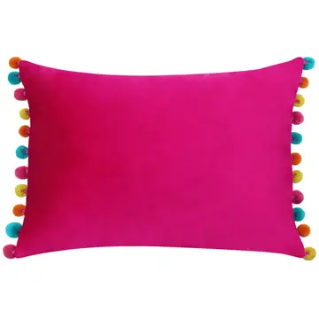A hot pink velvet cushion with multicolored pom-pom details on the corners.