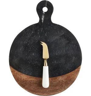 Round black marble cutting board with a wooden base and a cheese knife on a white background