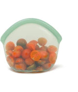 Clear silicone food storage bag with green lid filled with tomatoes on a white background