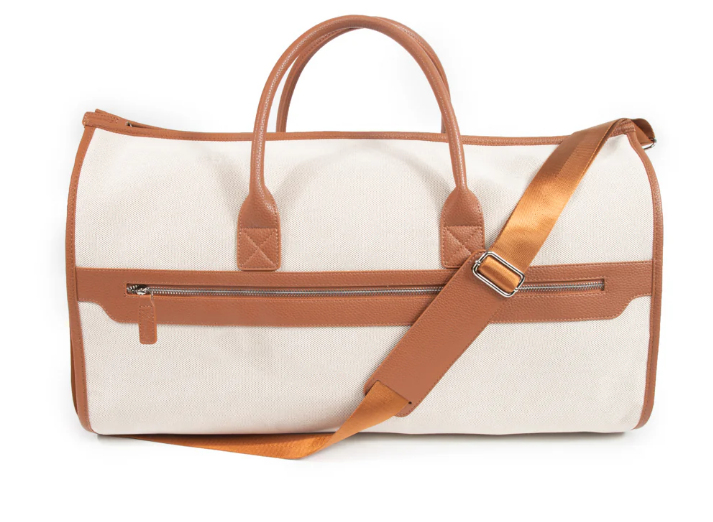 A beige and brown garment bag with vegan leather accents, featuring a shoulder strap and zipper compartments.
