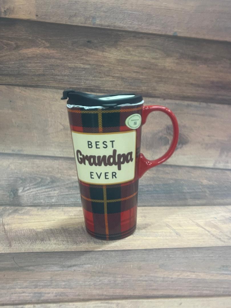 A ceramic travel cup with a plaid design, red handle, and a label reading 'BEST GRANDPA EVER' on it, displayed on a wooden surface.