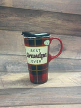 A ceramic travel cup with a plaid design, red handle, and a label reading 'BEST GRANDPA EVER' on it, displayed on a wooden surface.