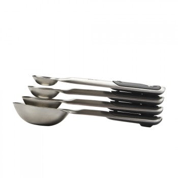 A set of four stainless steel measuring spoons of varying sizes arranged together.