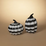 Two handblown glass pumpkins with black and white stripes on a beige background.