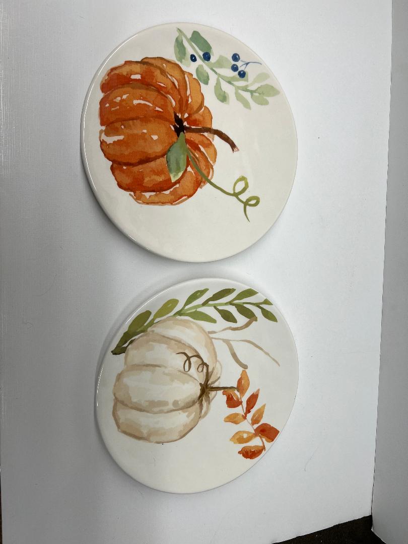 Two ceramic plates with painted pumpkins on a white background