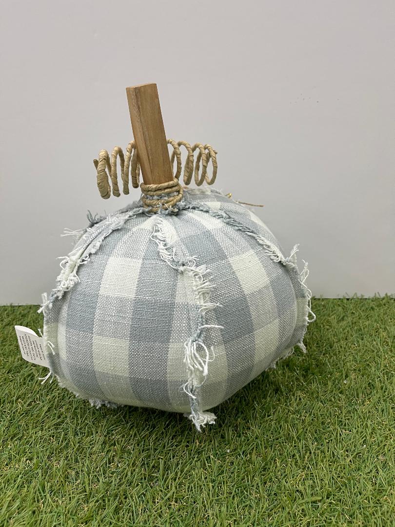Decorative pumpkin made of gray checkered fabric with a wooden stem on a grassy surface.