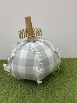 Decorative pumpkin made of gray checkered fabric with a wooden stem on a grassy surface.