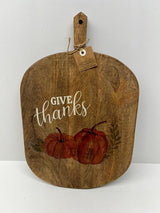 Wooden cutting board with 'Give thanks' and pumpkin design on a white background