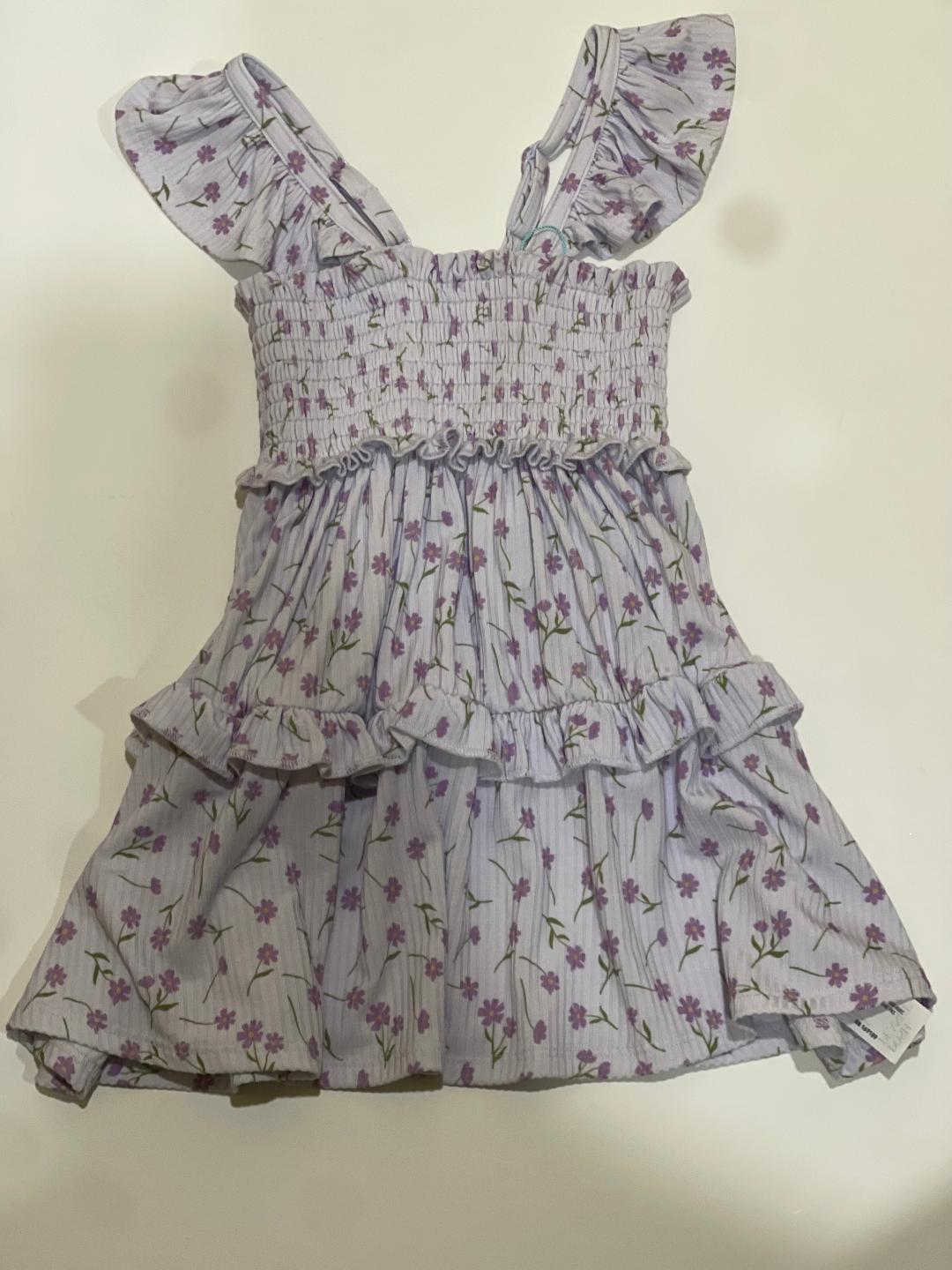 A toddler-sized dress with a floral pattern, short sleeves, and a round neckline.
