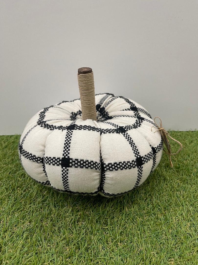 Decorative pumpkin with black and white plaid pattern on grass