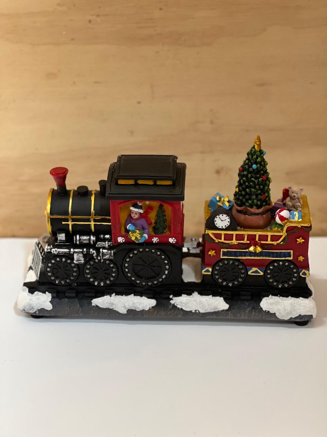 Toy train set with a Christmas tree and decorations on a wooden background