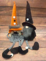 Two fabric gnomes designed for Halloween decoration, one with an orange hat and the other with a black hat, both with striped bodies and feet.