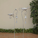 A silver cast iron birdbath with decorative elements, displayed outdoors.