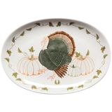 An oval-shaped ceramic serving platter with a cornucopia design, featuring an embroidered-like turkey in the center, surrounded by pumpkins and leaf patterns on a white background.