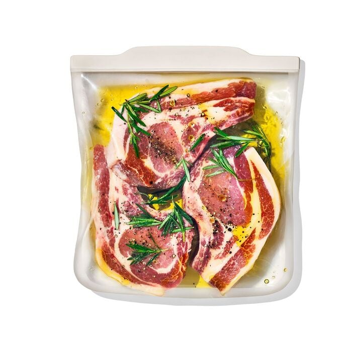 Raw marinated meat in a clear silicone reusable gallon bag.