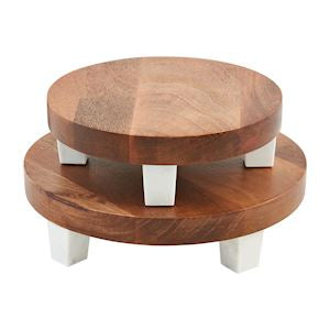 A two-tiered round wood marble riser with white supports.