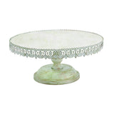A white cake stand with floral lace detailing around the top edge, having a sturdy base and a pedestal support.