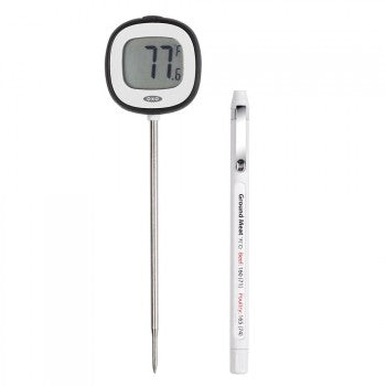 An OXO brand digital instant-read food thermometer with a black display showing the temperature, alongside a pen for taking notes.