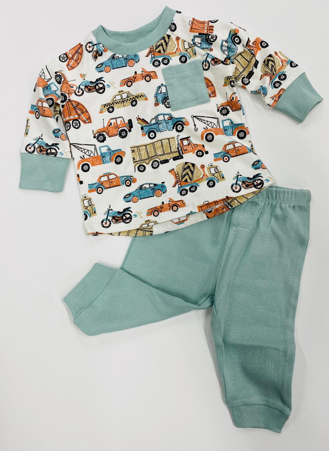 A set of children's clothing, with the top featuring a transportation theme in multicolor and the pants in solid green.