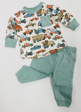 A set of children's clothing, with the top featuring a transportation theme in multicolor and the pants in solid green.