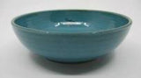 A blue ceramic pasta bowl on a white background.