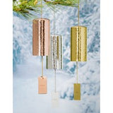 A set of metal wind bells in gold and silver colors, hanging against a snowy backdrop.