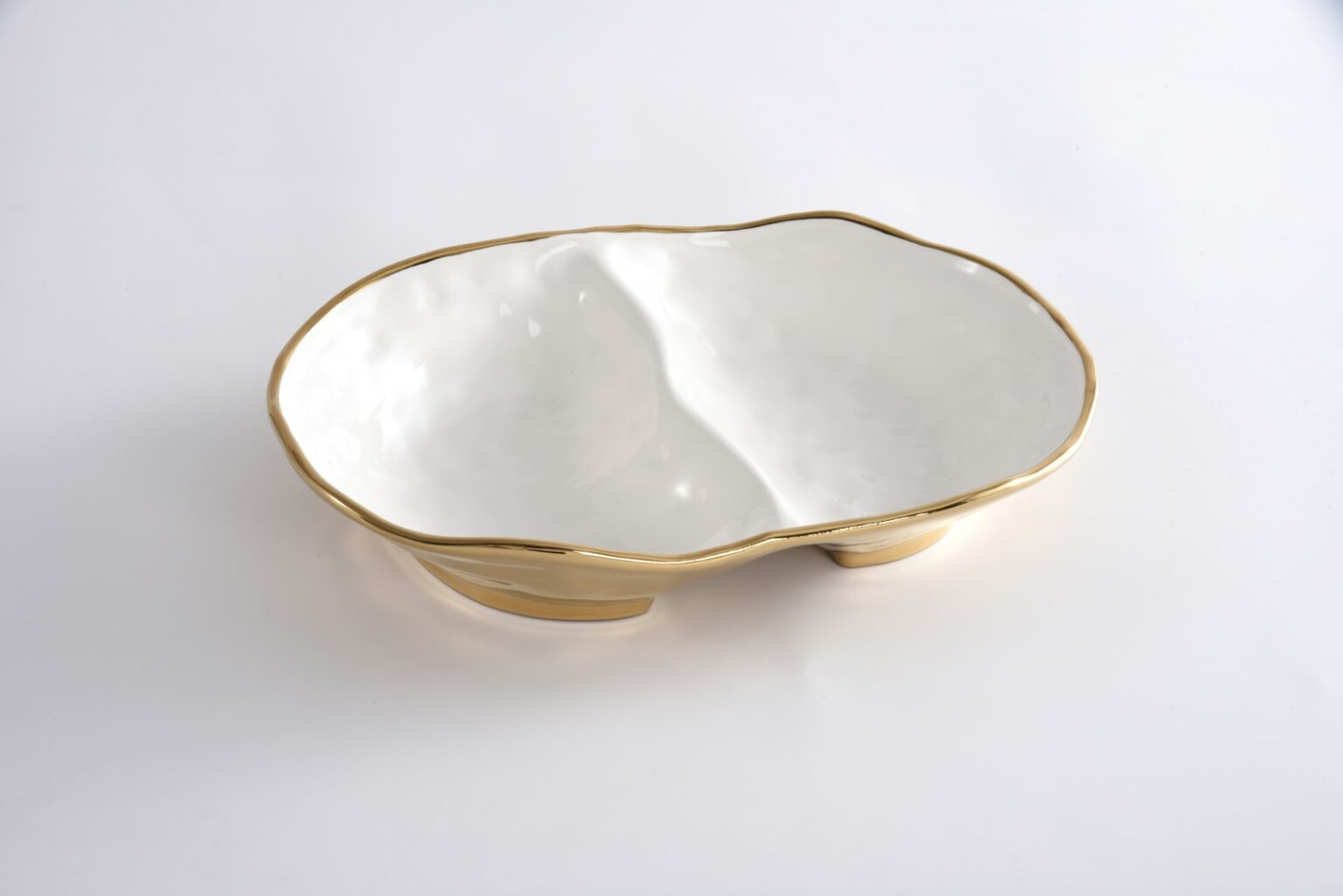 A two-sectioned serving bowl with a gold-colored rim and a white ceramic body.