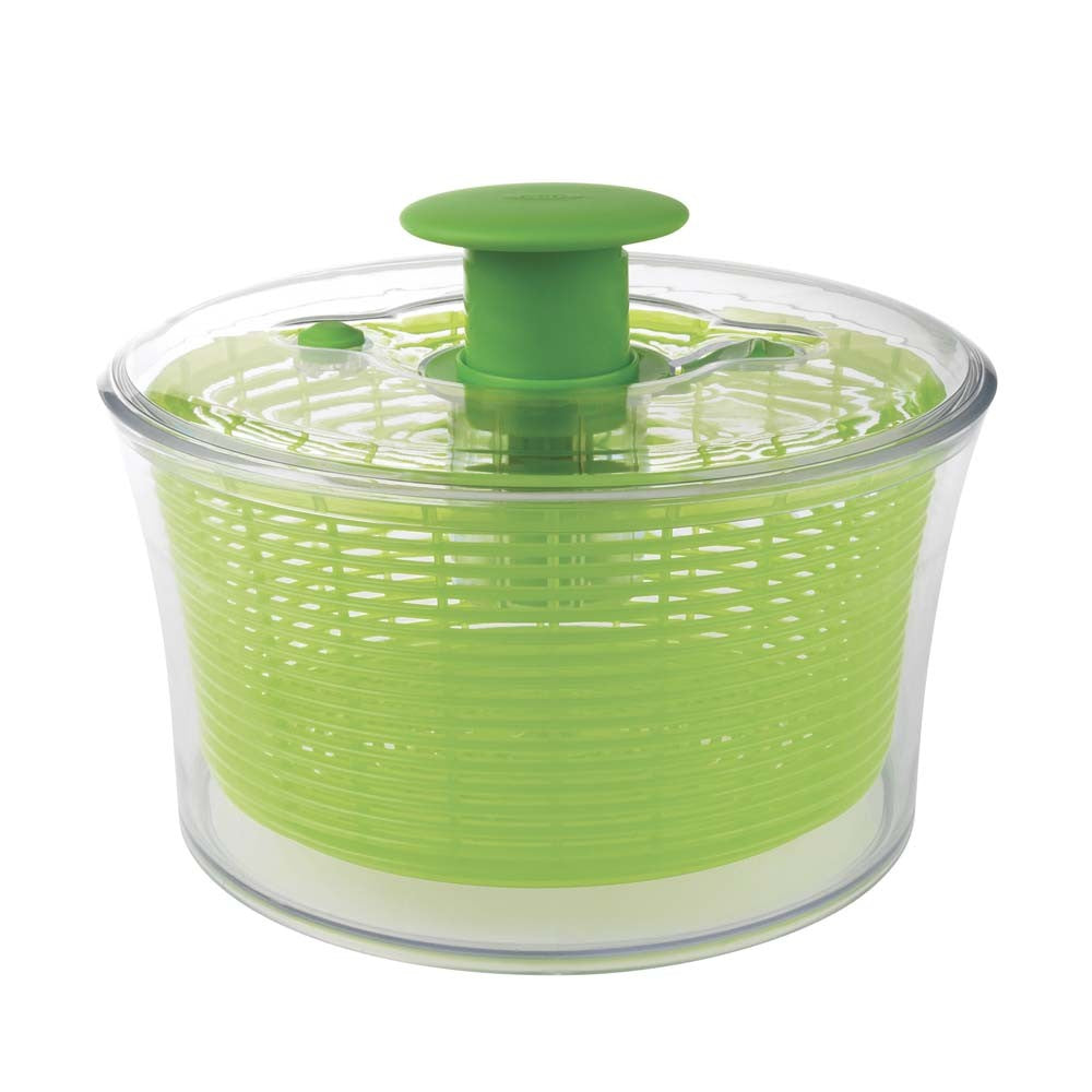 A green OXO salad spinner with a clear bowl and a green lid with a handle on the top.