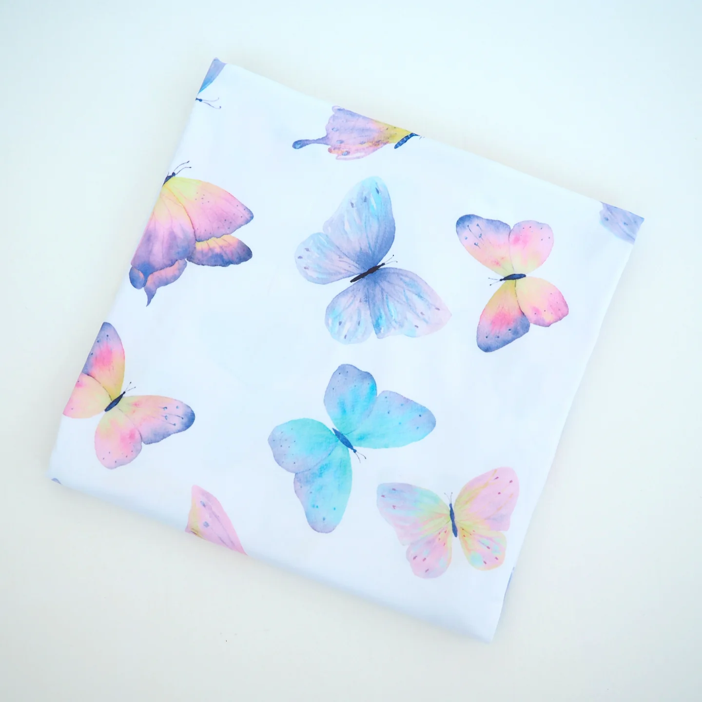 A swaddling blanket with a white background and colorful butterfly patterns.