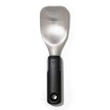 A stainless steel ice cream spade with a black handle, designed with a flat back and rounded edges for scooping ice cream.