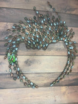 A decorative wall art piece with a unique design, featuring metallic elements and blue accents, laid out on a wooden floor.