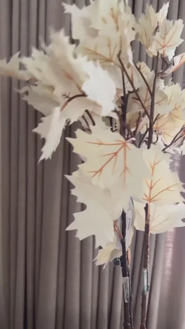A cream maple leaf spray decoration with intricate designed leaves placed in front of a window.