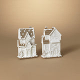 Two white resin gingerbread houses with brown roofs and decorative elements, displayed against a neutral background.