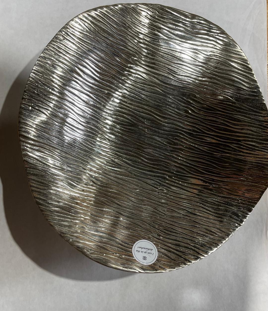 Round metallic tray with textured surface on a light gray background