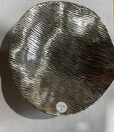 Round metallic tray with textured surface on a light gray background