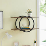 A wall-mounted shelf unit with crossed double circle design, featuring two shelves, one above the other, with books and a plant on the top shelf, placed against a yellow wall.