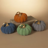 A collection of four resin and felt harvest pumpkins in orange, blue, green, and gray, with metal handles on top, displayed on a wooden surface.