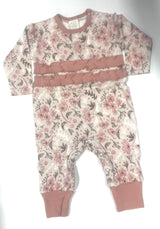 A floral patterned baby romper with ruffled detailing on the chest and around the legs.