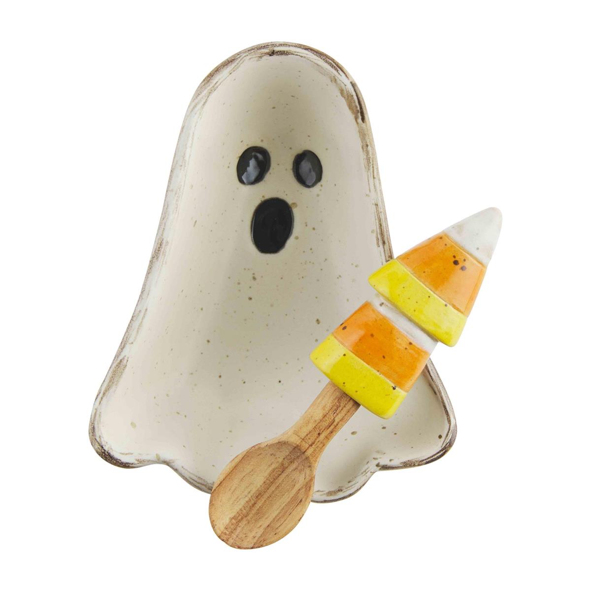 A beige ceramic candy bowl shaped like a ghost with a wooden spoon and candy corn design, against a white background.